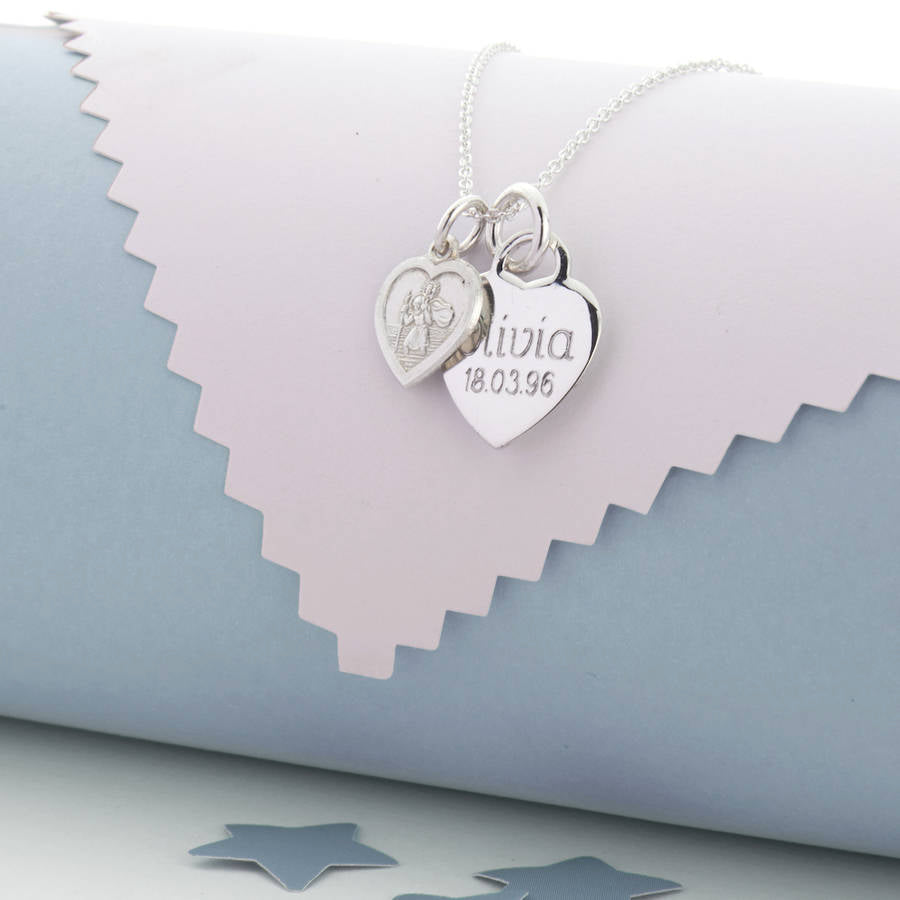 Silver necklace with a two heart pendants on, the smaller one a St Christopher, the larger one engraved with ‘Olivia 18.03.96’.