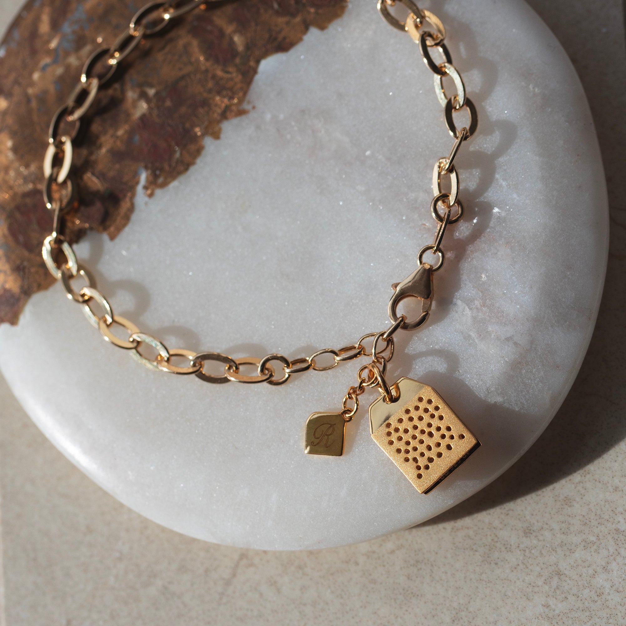 Gold bracelet with a heart-shaped charm on a white stone surface