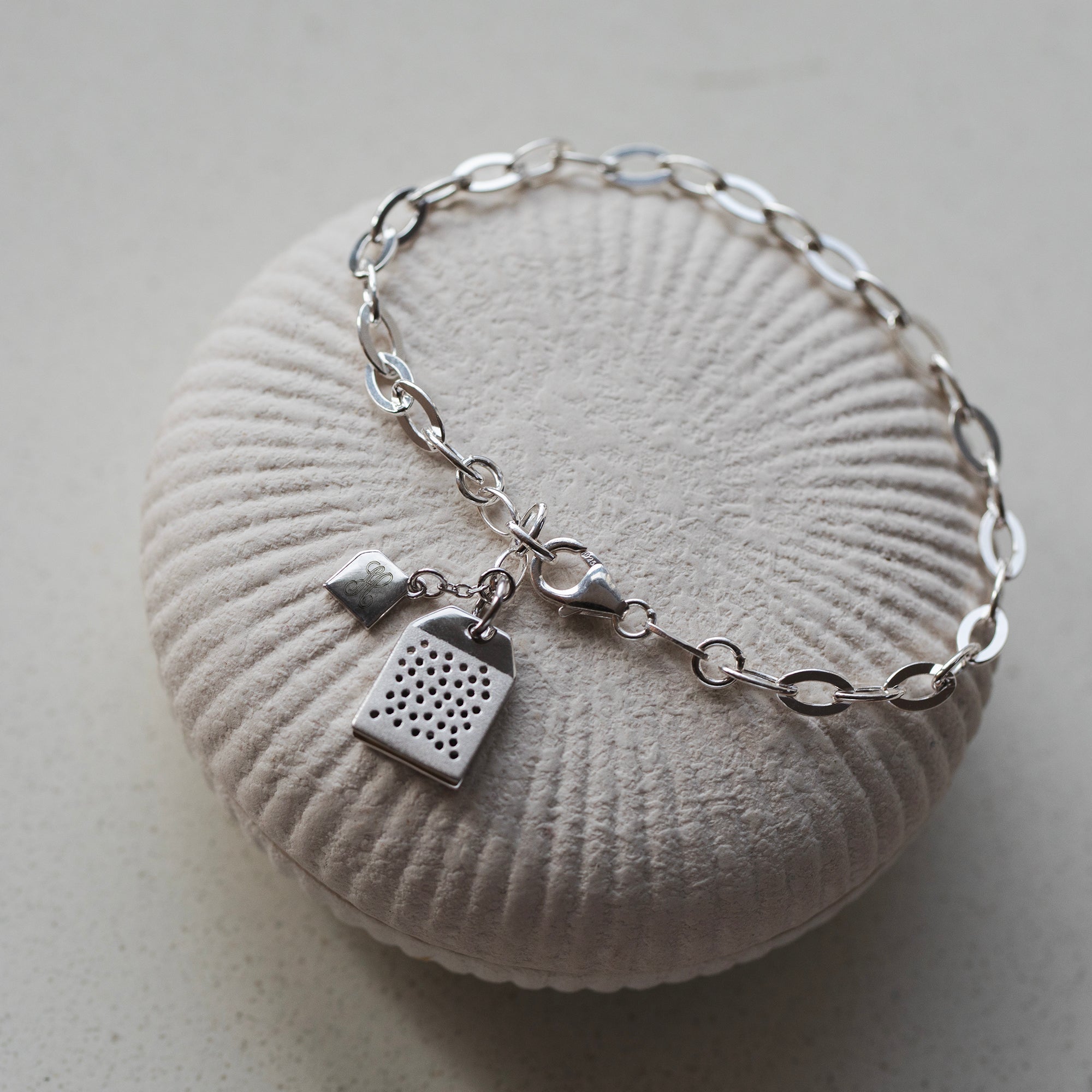 Silver bracelet with a unique charm on a textured white surface