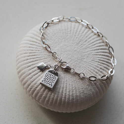 Silver bracelet with a unique charm on a textured white surface