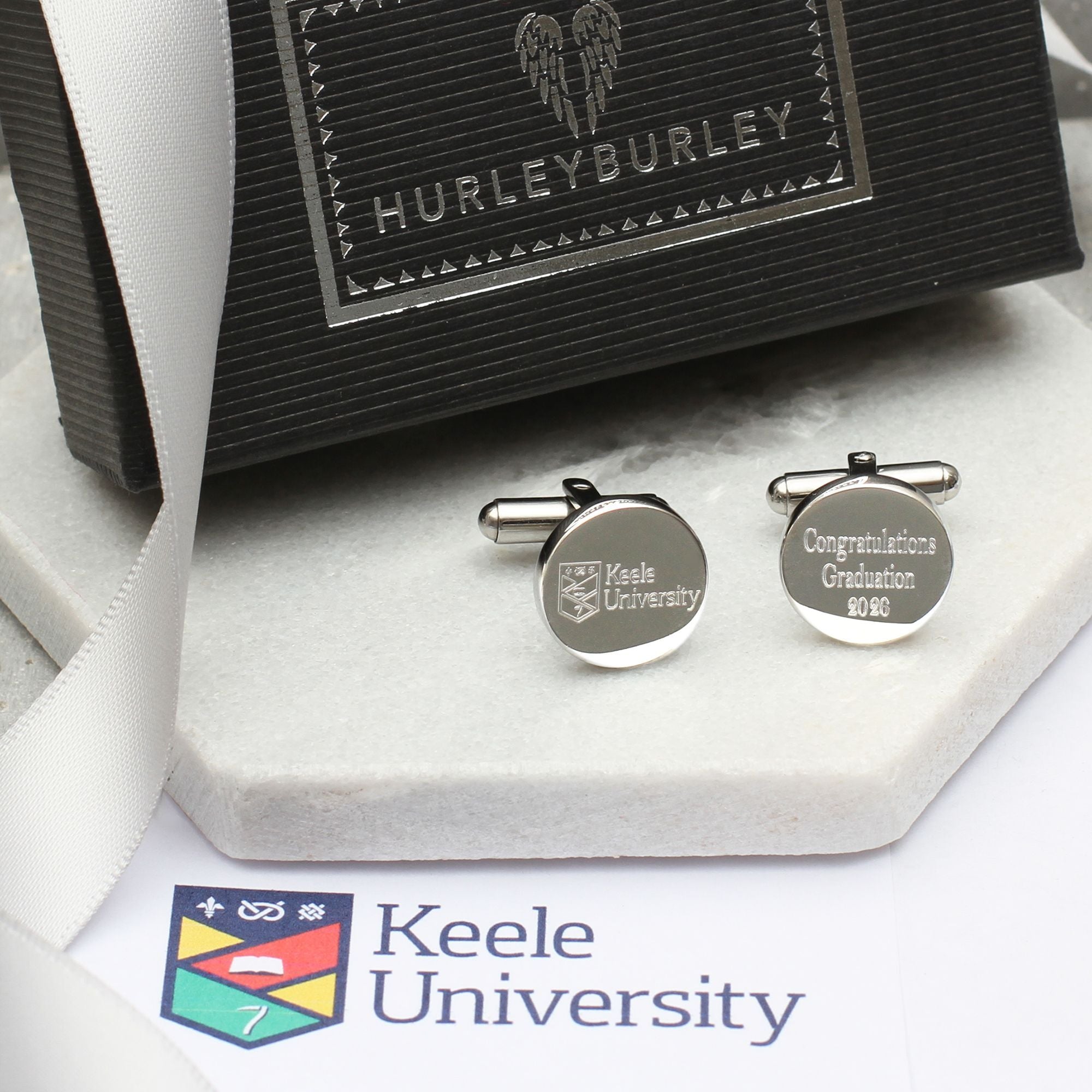 Silver cufflinks with 'Keele University' engraving on a Hurleyburley branded box.