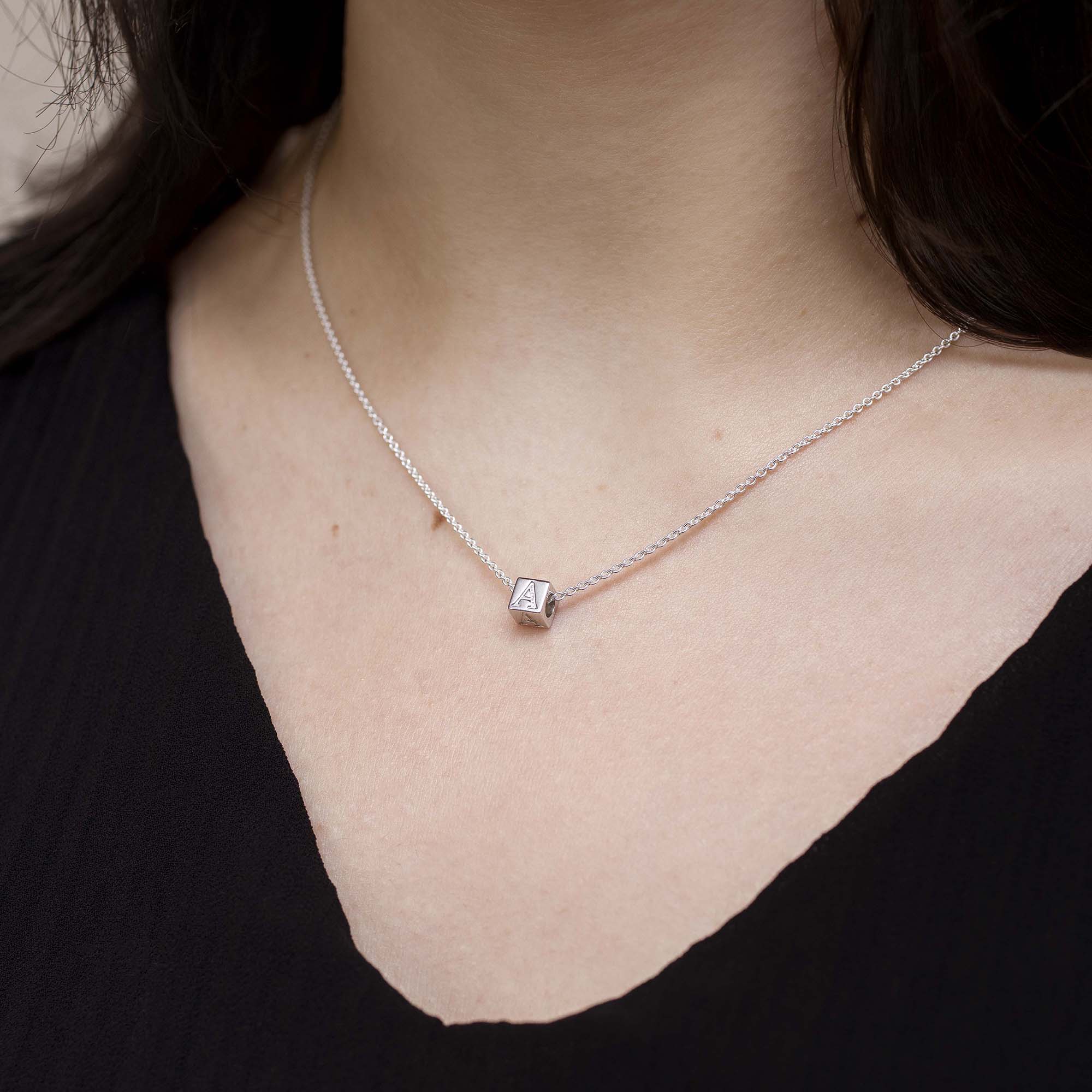 Necklace with a square pendant worn by a person against a neutral background
