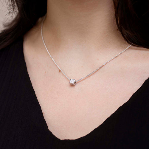 Necklace with a square pendant worn by a person against a neutral background