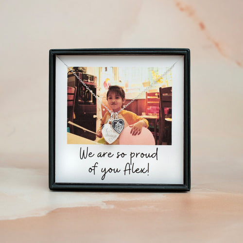 Framed photo of a child with a necklace, text 'We are so proud of you Alex!' on a light background