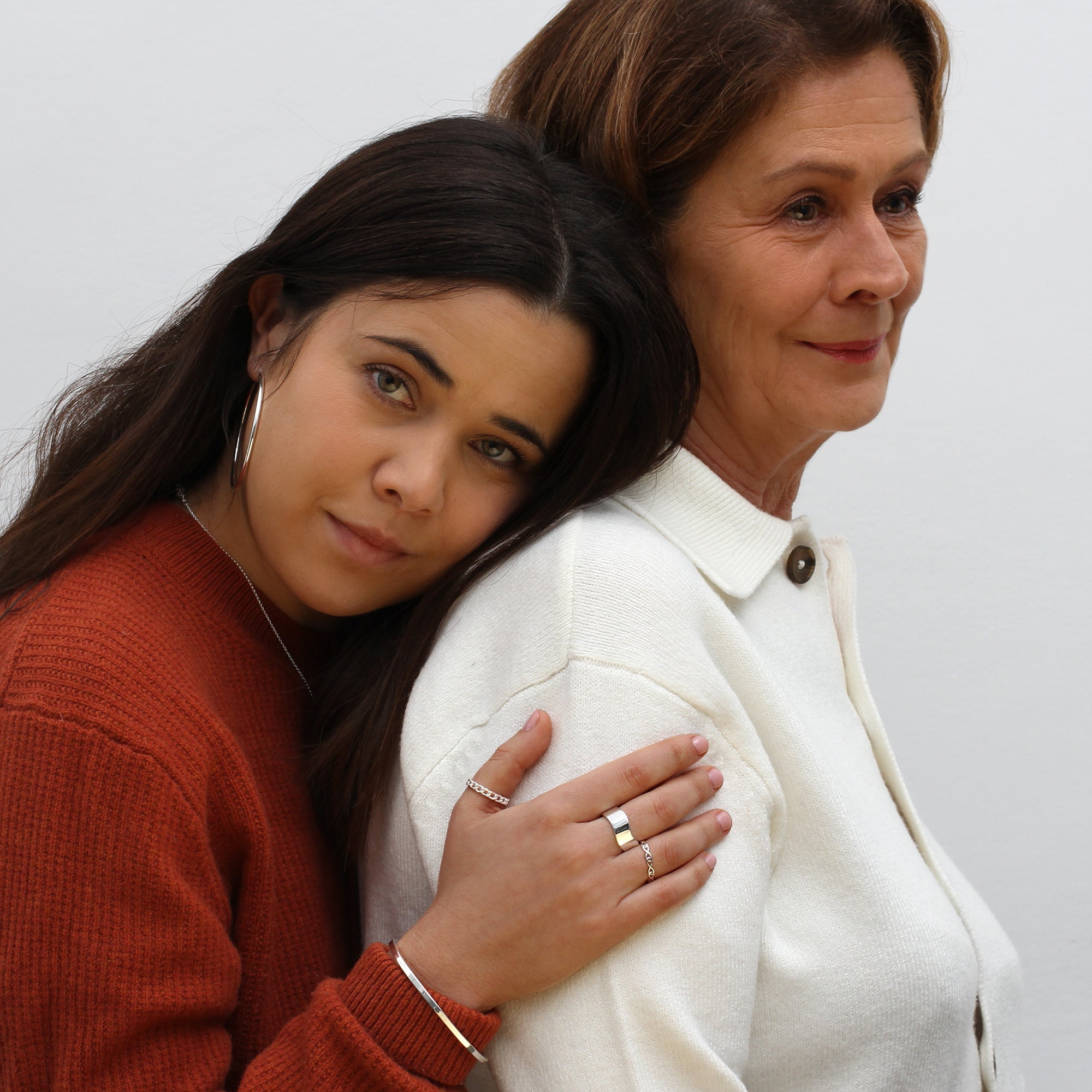 Two women standing close together with a plain background